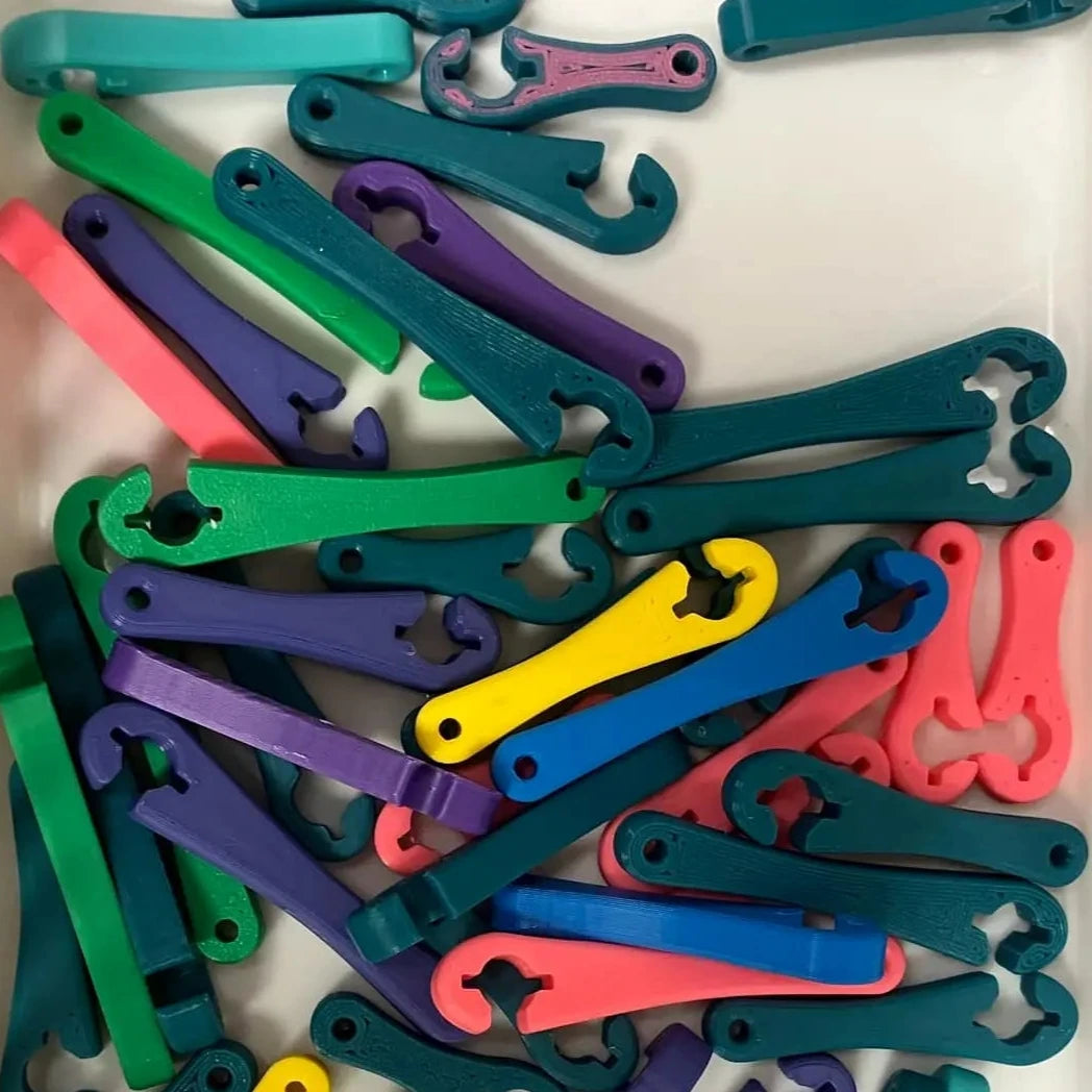 A collection of various colored EnFIT keychain wrenches laid out on a surface.