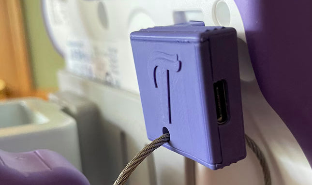 A lilac USB C charging adapter in the back of a kangaroo omni pump with a hanging keychain