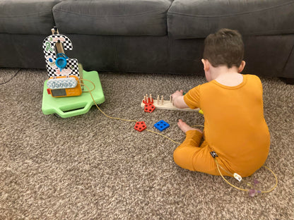 Child playing with toys on medium pile carpeting while their feeding pump rides on a Tubie Cart